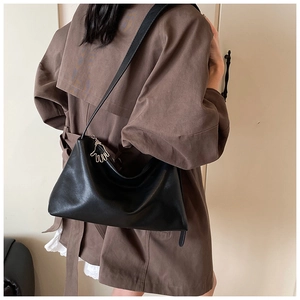 Détail d'un grand sac à main noir en cuir avec un pendentif doré en forme de main