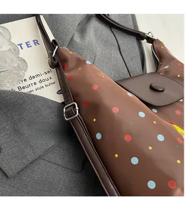 Detailed view of brown polka dot shoulder bag with adjustable strap on a gray blazer