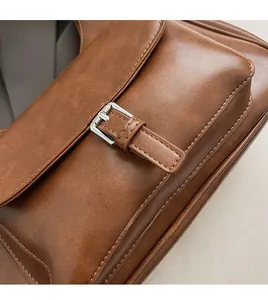 Detailed close-up of brown vintage shoulder bag featuring silver metal buckle and stitching