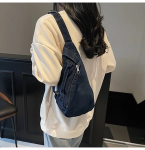 Detailed side view of large dark blue denim crossbody bag showing zipper pocket
