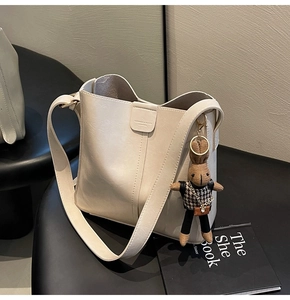 Close-up of cream white bucket bag featuring vertical stitching and a cute bunny charm