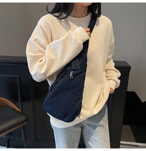 Close-up of a deep blue denim crossbody chest bag worn by a model in a casual setting