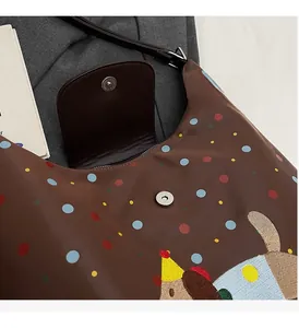 Detail of the magnetic buckle and colorful polka dot fabric on a brown crossbody bag