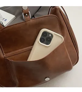Detailed view of the front magnetic pocket showing a smartphone inside a brown PU leather bag