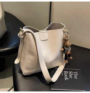 Close-up of cream leather tote bag with stylish bunny pendant and gold hardware