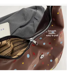 Detailed close-up of smooth silver zipper and striped lining on brown polka dot tote bag