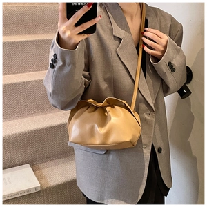 Détail d'un sac nuage plissé beige porté en bandoulière avec un blazer décontracté gris