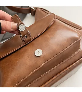 Macro detail of brown leather bag with silver magnetic snap and numbered buckle