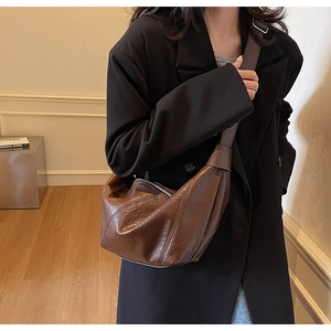 Detail of a dark brown half-moon crossbody bag in vintage leather on a model's shoulder