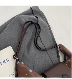 Detail of brown shoulder bag with colorful polka dots on a gray suit background