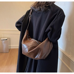 Detail of the brown pleated shoulder bag with adjustable strap and metal zipper