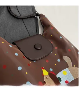 Detail of brown nylon shoulder bag featuring colorful polka dots and cartoon dog embroidery