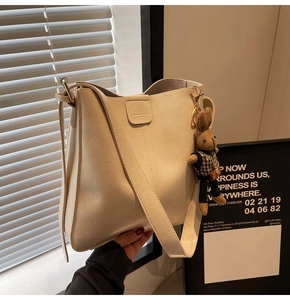 Detail of cream white bucket bag with pebble texture and cute rabbit charm