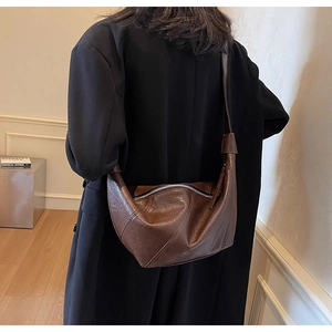 Detail of dark brown leather hobo bag showing contrast stitching and silver zipper closure