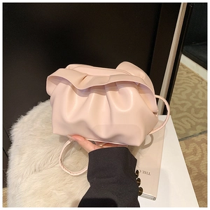 Gros plan d'un sac nuage plissé rose clair en cuir tenu par un mannequin élégant