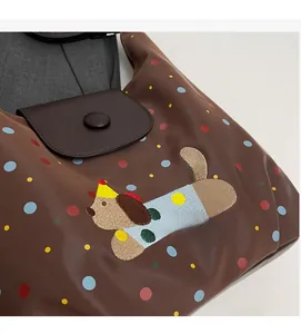 Detail of dark brown nylon bag featuring colorful dots and cartoon dog embroidery