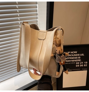 Detail of off-white bucket bag featuring fine leather texture and cute rabbit charm pendant