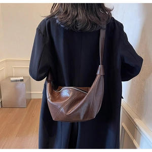 Detailed view of brown leather crescent bag showing natural oil texture and pleated finish