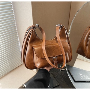 Detail of caramel vintage underarm bag with metal buckle and soft leather texture