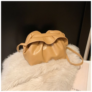 Détail du sac dumpling plissé marron clair en cuir mat sur fausse fourrure blanche