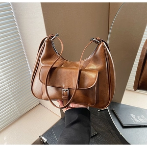 Detailed view of dark brown leather shoulder bag featuring a front pocket with metal buckle