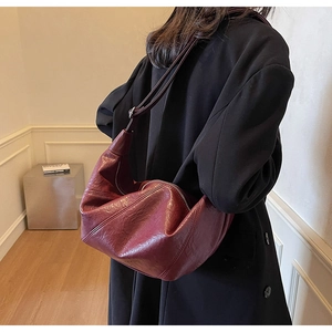 Detailed view of dark wine red wrinkled crescent bag with vintage faux leather texture