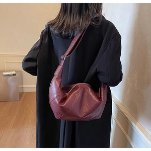Detail of burgundy leather hobo bag with adjustable strap and silver zipper closure