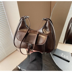 Detail of dark brown glossy leather underarm bag with vintage buckle pocket design