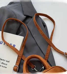 Detail of adjustable silver buckle and metal clasp on brown suede small square bag