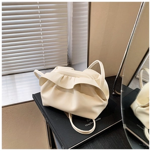 Vue détaillée du sac nuage plissé crème montrant la texture froncée sur fond de livres