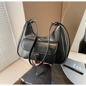 Detail of black faux leather crescent bag with silver buckle pocket and adjustable strap