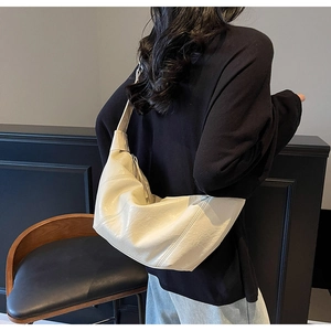 Model view of large ivory dumpling shoulder bag showing drape and size on shoulder
