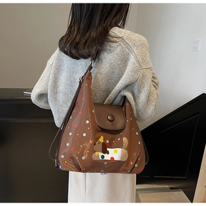 Close-up of brown polished tote bag with puppy embroidery and dots on model