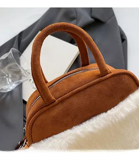 Detail of plush faux fur and brown suede on a stylish winter handbag with gold zipper