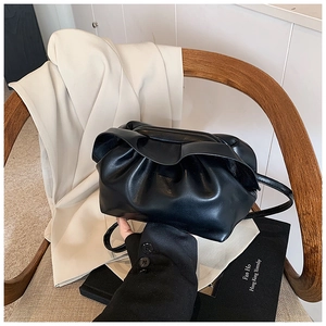 Détail du sac nuage plissé noir sur chaise en bois avec une esthétique minimaliste