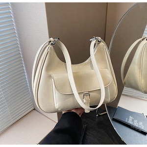 Detail of cream half-moon underarm bag with glossy leather finish and silver buckle