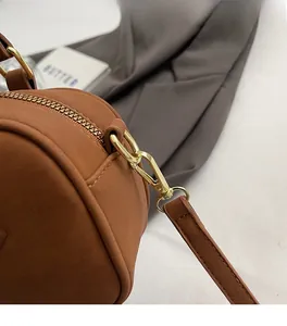 Macro shot of premium gold hardware and fine stitching on a brown suede crossbody bag