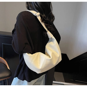 Detail of off-white crescent bag with litchi grain texture and adjustable strap
