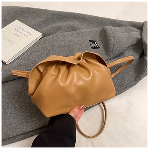 Détail du sac nuage plissé marron clair sur manteau gris avec livre d'art