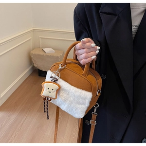 Detail of brown suede mini bag with white faux fur trim and cute toast plush charm