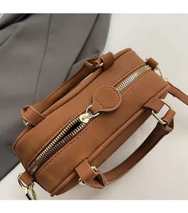 Close-up of smooth gold metal zipper and stitching on the brown suede bowling handbag