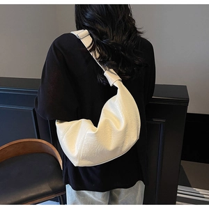 Detail of creamy crescent bag with soft pleated leather texture and wide shoulder strap