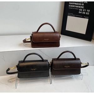Three vintage flap crossbody bags in tan, black and dark coffee on a modern display stand