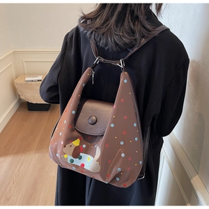 Detail view of brown glossy backpack with colorful dots and cartoon puppy on model back