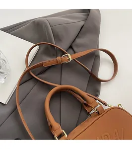 Detail of adjustable caramel brown leather shoulder strap with golden metal buckle clasp