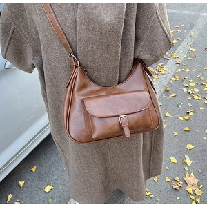 Detail of vintage dark brown faux leather crossbody bag with buckle and front pocket