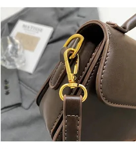 Detailed close-up of premium gold-tone metal hooks and ring hardware on brown leather bag