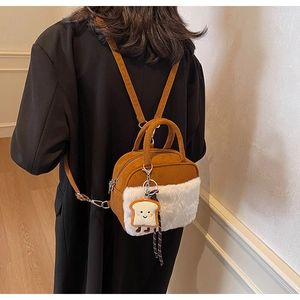 Detail view of caramel suede and white faux fur small square bag with toast plush pendant