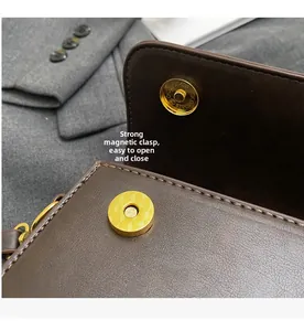 Detail of dark brown leather handbag featuring a strong gold magnetic snap button closure