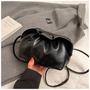 Détail du sac nuage plissé noir avec finition mate sur un manteau en laine grise